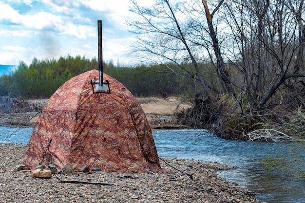 Tente touristique sur la rive du fleuve dans les montagnes. Les touristes vivent au bord de la rivière dans la tente