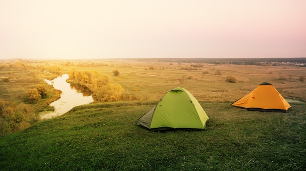 Tente verte et orange au bord de la rivière