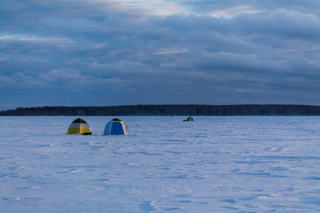 Tentes de pêche sur le lac gelé et enneigé