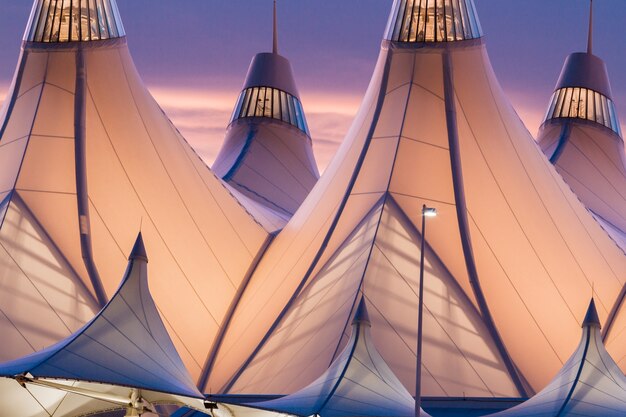 Photo tentes rougeoyantes de dia au lever du soleil. l'aéroport international de denver est bien connu pour son toit pointu. la conception du toit reflète les montagnes enneigées.