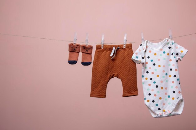 Tenue de bébé mignon suspendu à une ligne sur un fond rose