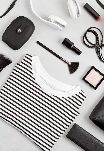 Photo tenue de mode femme et accessoires, sac à main, bloc-notes, maquillage et écouteurs aux couleurs noir et blanc. concept de beauté, tenue urbaine et tendances de la mode. mise à plat, vue de dessus