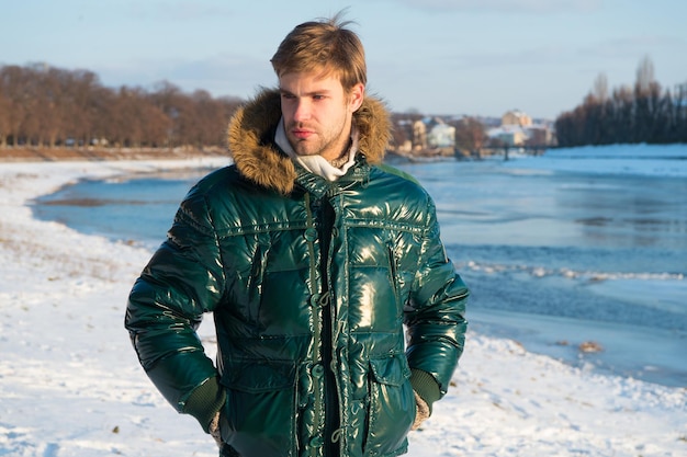 Tenue de mode d'hiver hipster. Guy porter une veste avec capuche le jour d'hiver glacial. Vêtements résistants au vent. Vêtements pour hommes élégants d'hiver. Tenue d'hiver. Homme barbu stand veste chaude fond de nature enneigée.