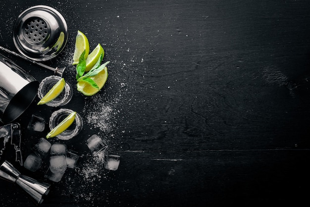 Tequila au citron vert et glace sur une surface en bois noire Vue de dessus Espace libre