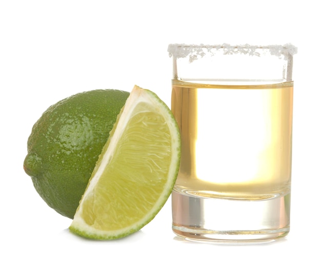 Tequila d'or dans un verre avec du sel et de la chaux sur fond blanc isolé. breuvages alcoolisés. fermer.