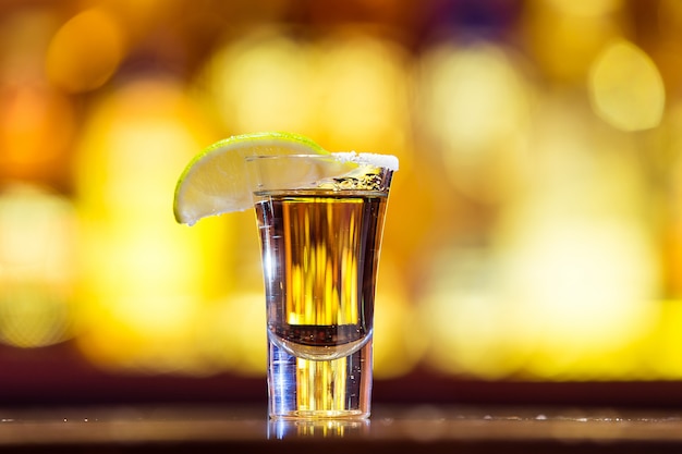 Tequila or dans un verre sur des lumières vives. Boisson mexicaine traditionnelle.