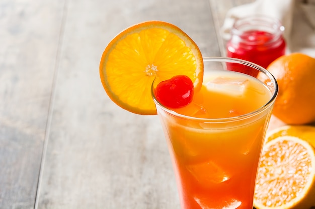 Tequila sunrise cocktail en verre sur une table en bois.