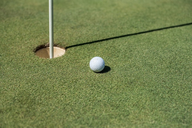 Terrain de golf avec balle blanche près du trou