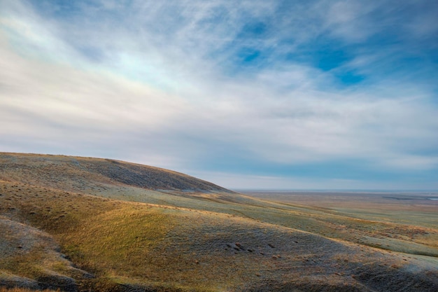 Un terrain herbeux avec un ciel bleu et des nuages en arrière-plan.