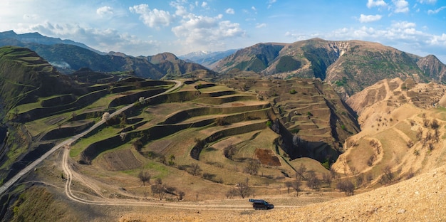 Terrain de montagne avec un petit minibus près de la montagne. Hautes montagnes, paysage montagneux complexe, terrasses verdoyantes couvertes de pentes végétales clairsemées. Daghestan