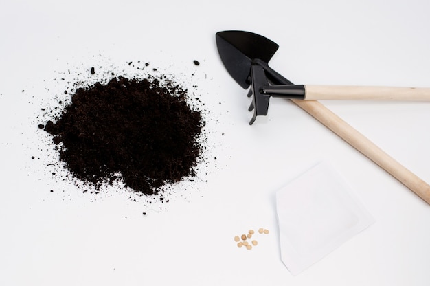 Terrain pour planter des graines, un sac de graines de tomates éparses et un râteau et une pelle en bois