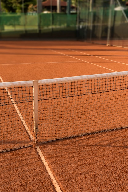Terrain de tennis en terre battue, sous le coucher du soleil.