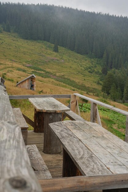 Terrasse de café avec tables en bois parmi les montagnes et beaucoup d'arbres