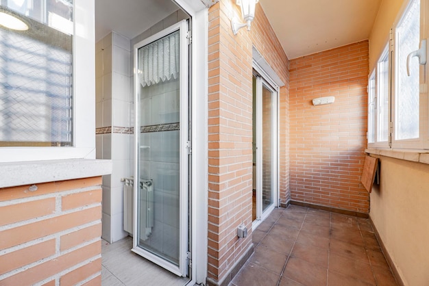 Terrasse fermée dans une maison d'habitation urbaine avec accès à une cuisine en carrelage blanc avec bordure marron