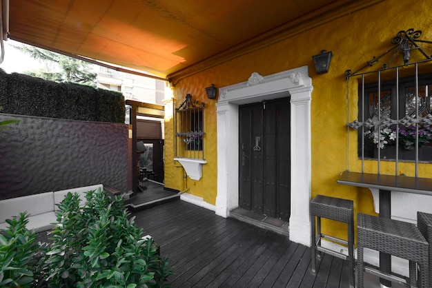 Terrasse et hall avec parquet en bois foncé, porte à panneaux en bois et plantes vertes