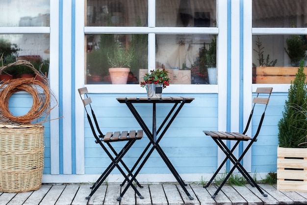 Terrasse d'hiver avec paniers en osier et plantes vertes en pots sur le porche de la maison.