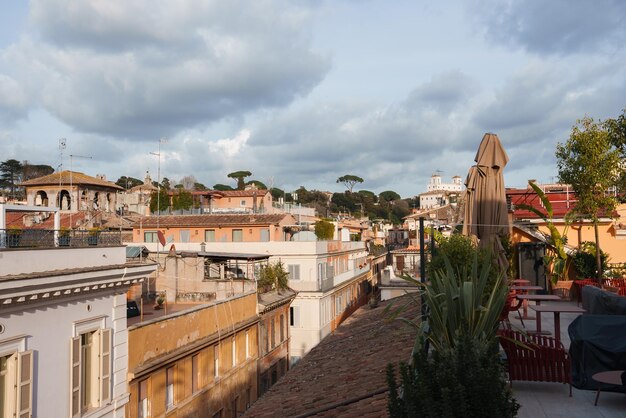 Terrasse de luxe sur le toit d'un hôtel à Rome avec des chaises rouges, des tables et des plantes surplombant le paysage urbain