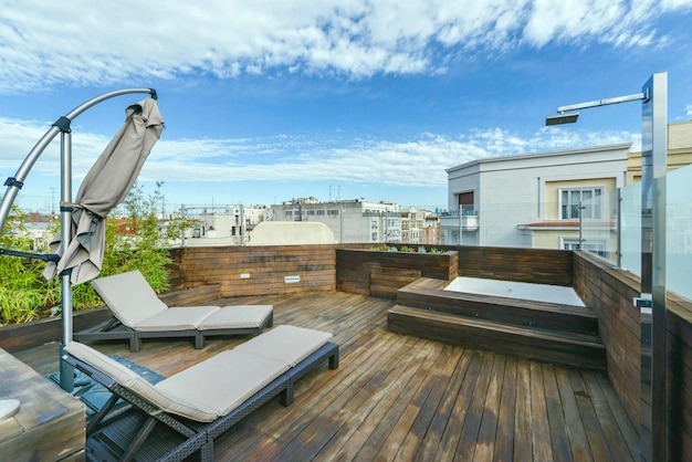 Photo terrasse penthouse recouverte de planches de bois avec hamacs et jacuzzi dans un appartement de location de vacances