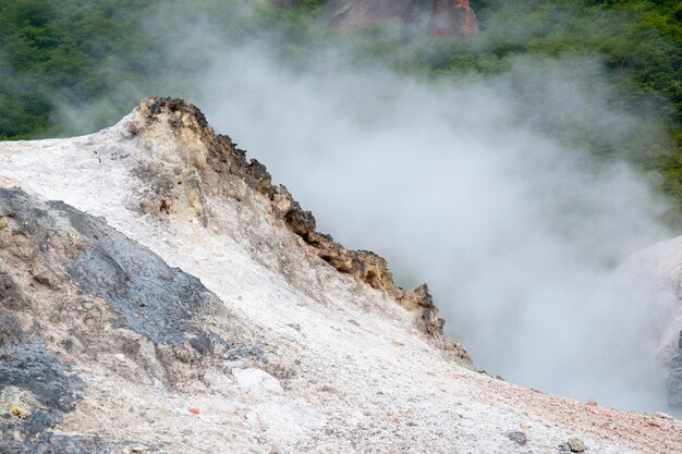 Terre volcanique colorée avec de la vapeur chaude derrière des sables minéraux colorés