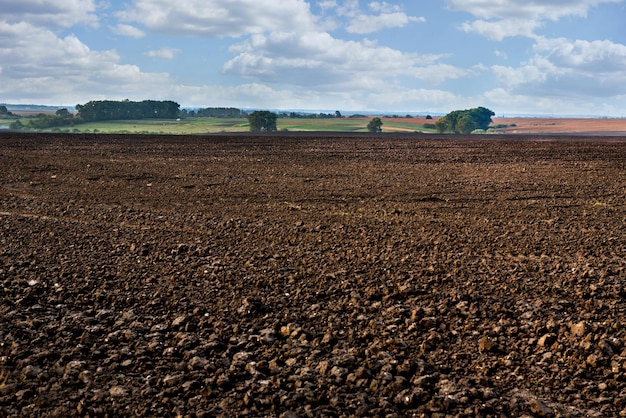 Terres labourées au premier plan, bosquets et collines en arrière-plan des terres rurales