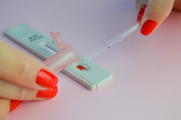 Test de coronavirus sur fond rose mat procédure médicale lancette rose pour le perçage des doigts