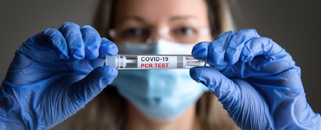 Test COVID19 dans les mains du médecin en gros plan une femme portant un masque médical tient un tube de test PCR de coronavirus