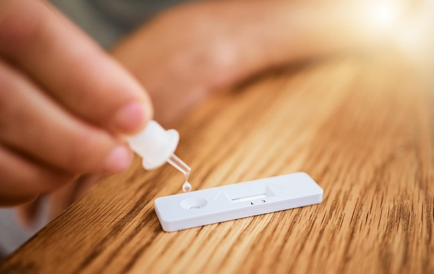 Test à domicile corona et covid pour les maladies virales et les maladies pendant le verrouillage à l'intérieur Zoom avant des mains à l'aide d'outils médicaux pour un test d'antigène pour les résultats covid sur une table à l'intérieur pour la sécurité