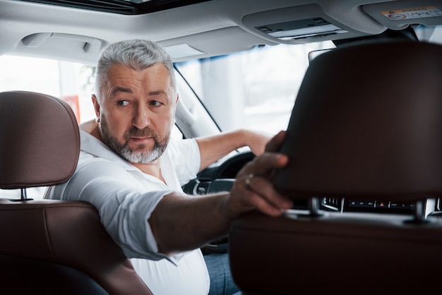 Test du véhicule. Conduire une voiture en marche arrière. Regardant derrière. Homme dans sa toute nouvelle automobile