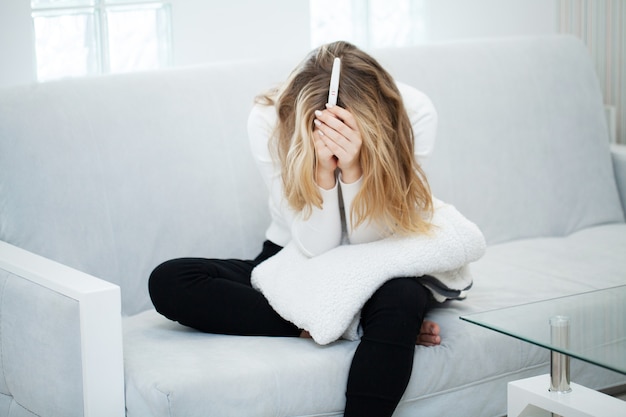 Test de grossesse. Femme triste inquiète regardant un test de grossesse après le résultat.