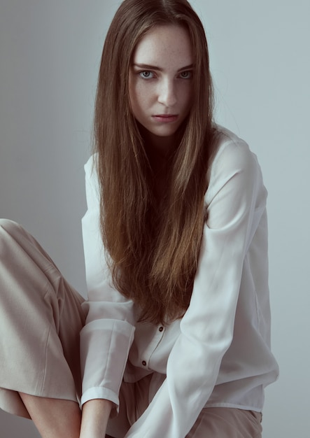 Test De Modèle Avec Une Belle Jeune Mannequin Aux Cheveux Longs Portant Une Chemise Blanche Sur Fond Gris