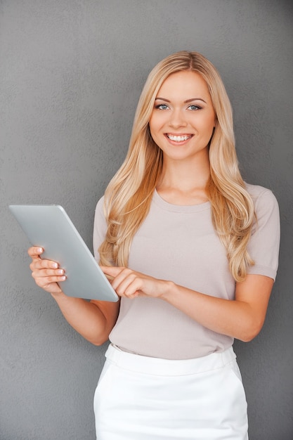 Test de son nouveau gadget. Souriante jeune femme travaillant sur tablette numérique et