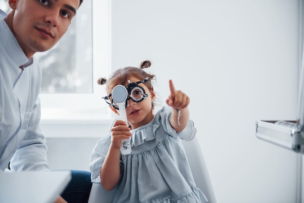 Tester la vue. Le jeune ophtalmologiste est avec une petite visiteuse à la clinique.