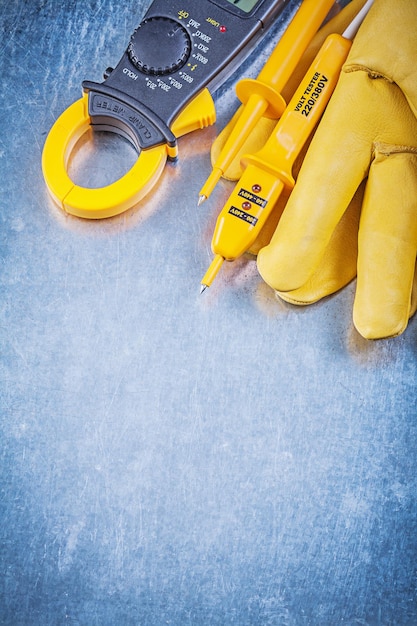 Testeur électrique d'ampèremètre numérique gants de protection sur le concept d'électricité de surface métallique.