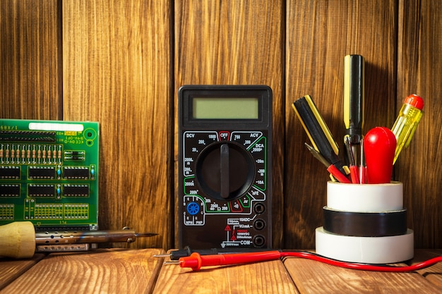 Testeur électrique et un ensemble d'outils pour la réparation électronique sur fond de bois vintage.