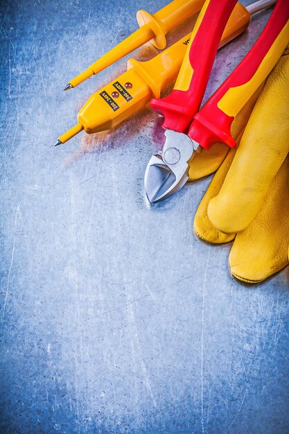 Testeur électrique jaune gants de sécurité coupe-fil pointu sur fond métallique concept d'électricité