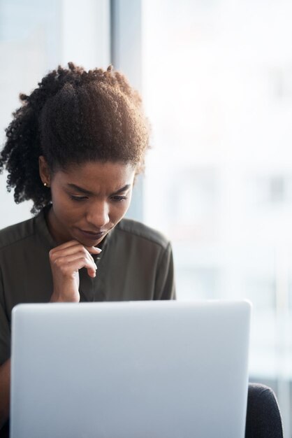 Tête baissée pour travailler dur Photo d'une jeune femme d'affaires utilisant un ordinateur portable dans un bureau moderne