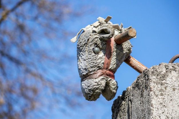 Une tête de cheval039s jouet sur un bâton en bois sur une clôture en béton contre un ciel bleu