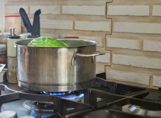 La tête de chou est cuite dans une casserole sur une cuisinière à gaz