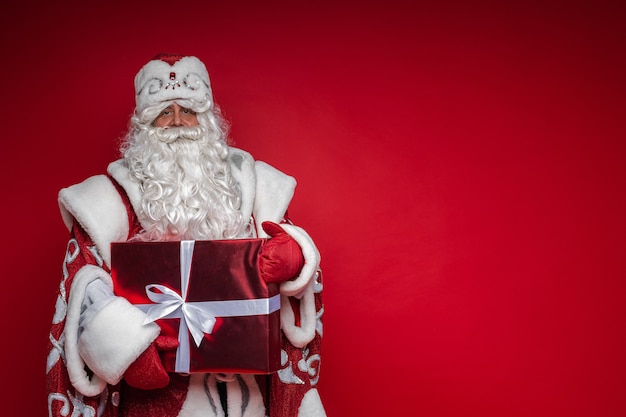 Tête du Père Noël au chapeau rouge, homme fatigué aux cheveux gris sur fond gris studio. photo de haute qualité