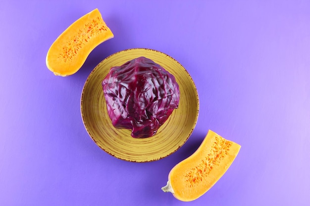 Une tête entière de chou violet sur une plaque jaune sur fond violet Concept de cuisine végétarienne Gros plan