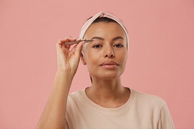 Tête et épaules portrait de belle femme métisse plumer les sourcils