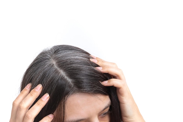 Tête de femme aux cheveux grisonnants sur fond blanc. Le concept des premiers cheveux gris.