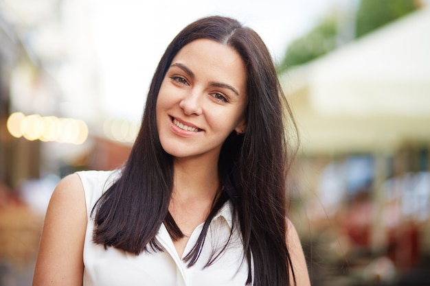 Tête de femme brune sourit joyeusement