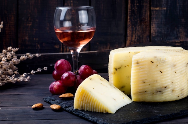 Tête de fromage fait maison à la lavande sur une vieille planche de bois sombre et un verre de vin sur la table. Produits laitiers frais, aliments biologiques sains. Délicieux apéritif.