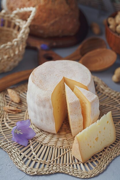 Une tête de fromage frais bio servie avec du pain, des noix, du vin blanc et des fleurs d'été. Concept d'aliments sains et biologiques.