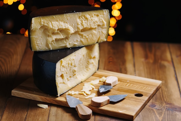 Photo tête de fromage à pâte dure moyenne parmesan sur planche de bois avec des couteaux au fromage parmesan