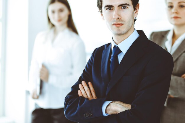 Tête d'homme d'affaires debout tout droit avec des collègues à l'arrière-plan du bureau. Groupe de gens d'affaires discutant de questions lors d'une conférence ou d'une présentation. Succès et concept d'entreprise.