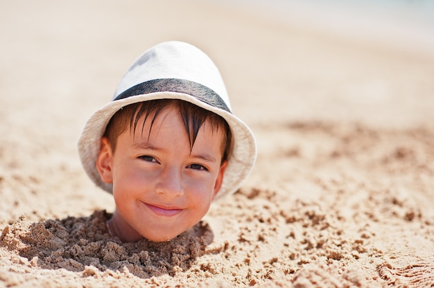 Tête de jeune garçon sur le sable porter un chapeau de Panama. Vacances d'été drôles.