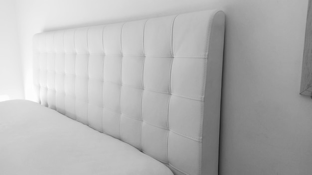 Tête de lit souple Rembourrage pour meubles en cuir véritable ou artificiel et tissu matelassé Tête de lit souple contre un mur clair Photo monochrome en noir et blanc