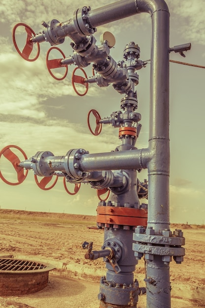 Tête de puits avec armature de vanne sur un champ pétrolifère. Concept de l'industrie pétrolière et gazière. Contexte du site industriel. Extraction d'huile. Sépia tonique.